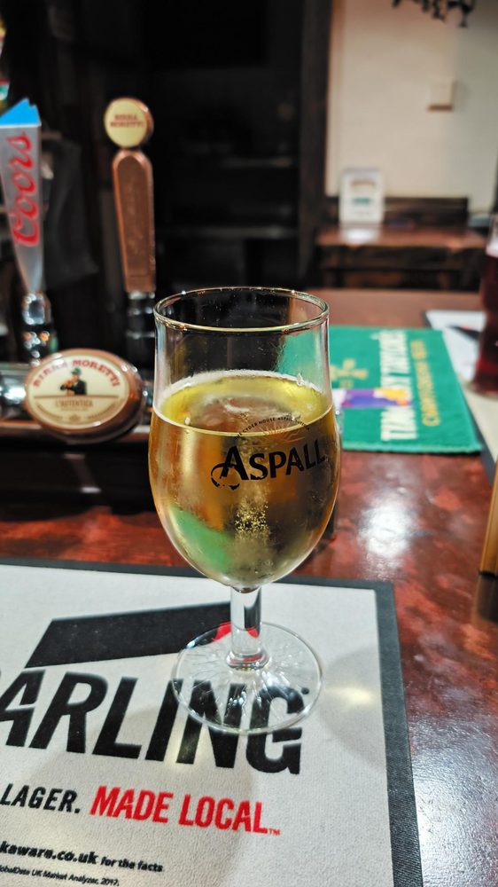 Glass of Aspall cider on the bar with Coors and Birra Moretti draught taps visible behind