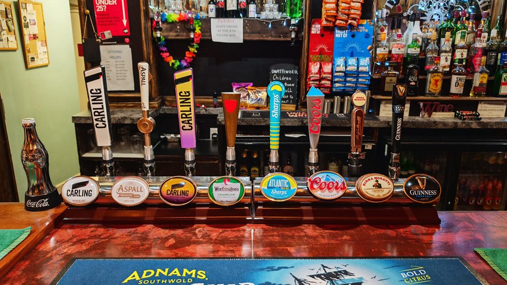 Close-up of draught taps showing Carling, Aspall, Worthington's, Atlantic, Coors, and Guinness with an Adnams bar mat