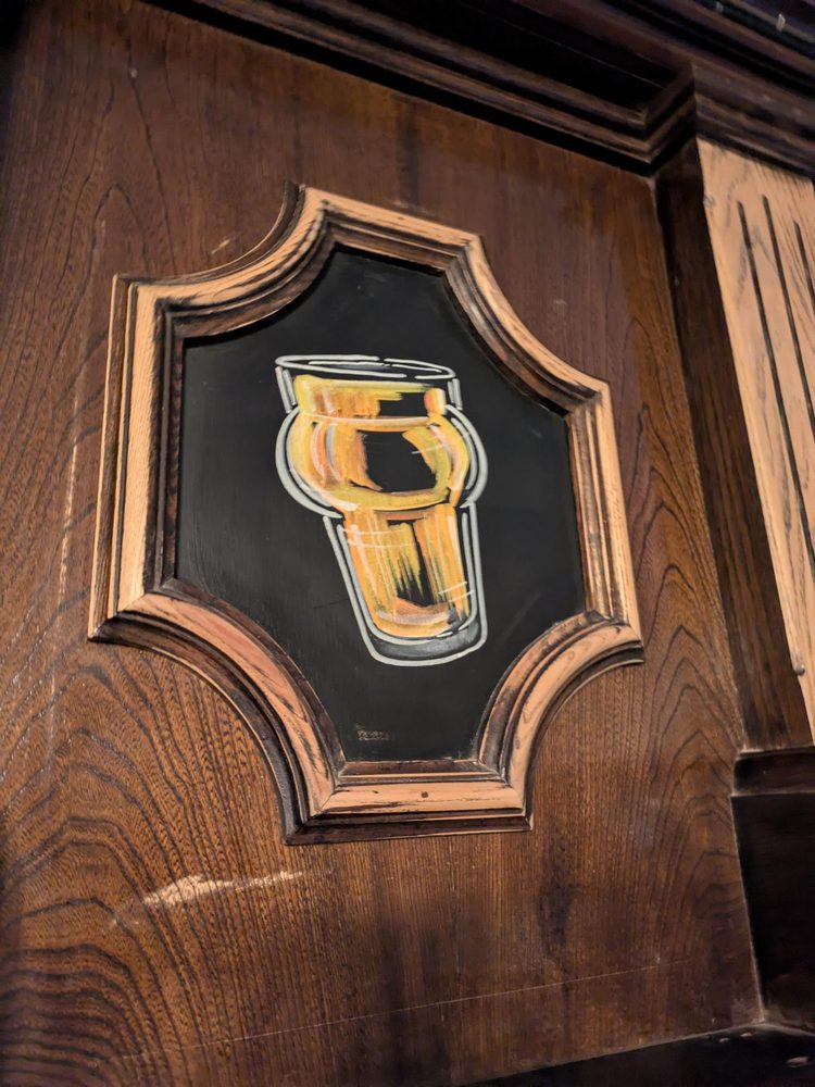 Hand-painted artwork of a pint glass on one of the wooden panels behind the bar