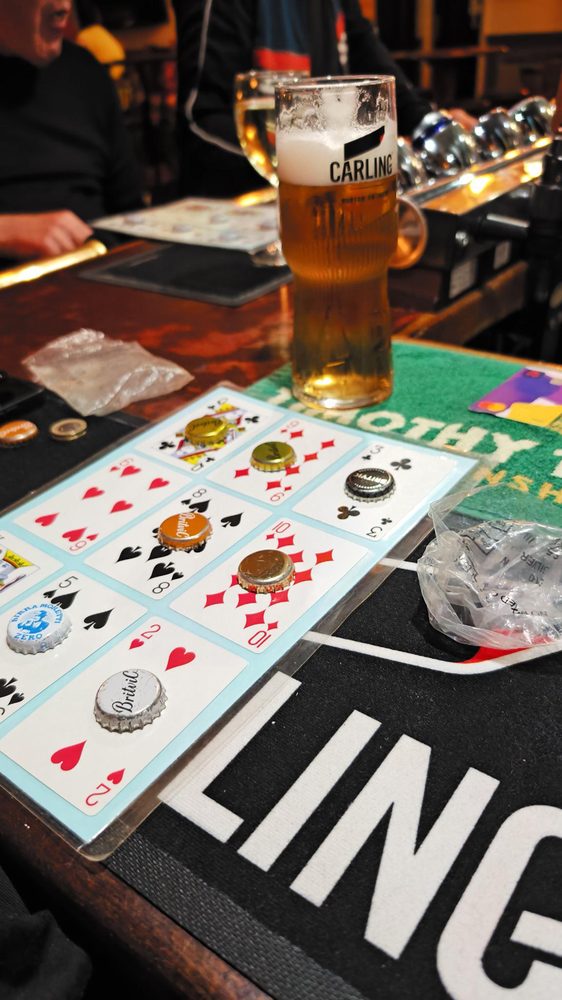 Hoy card game with bottle caps and a pint of Carling