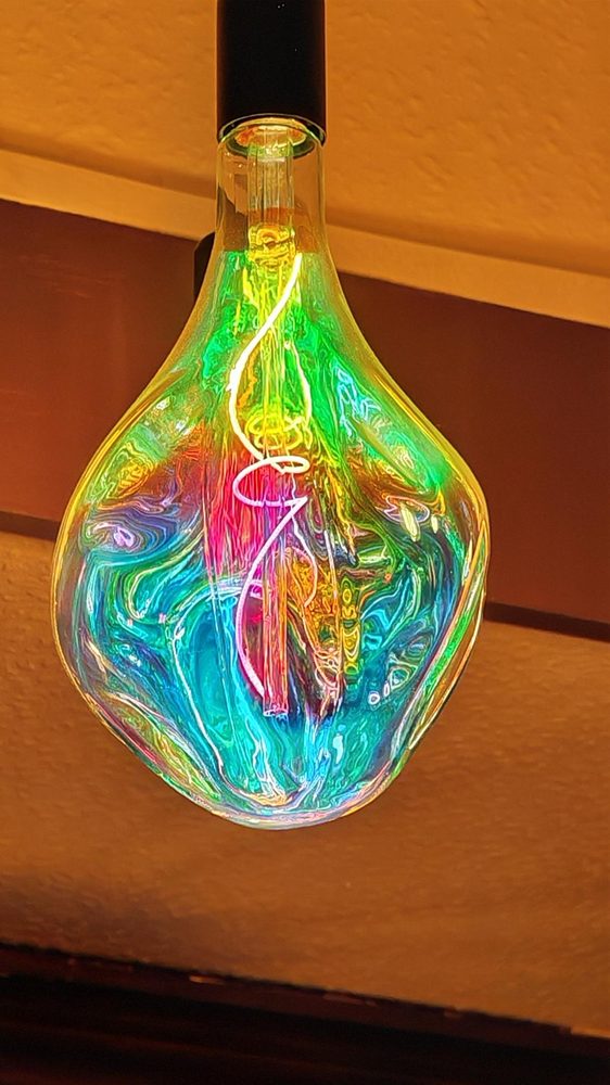 Close-up of a decorative light bulb glowing with rainbow colours